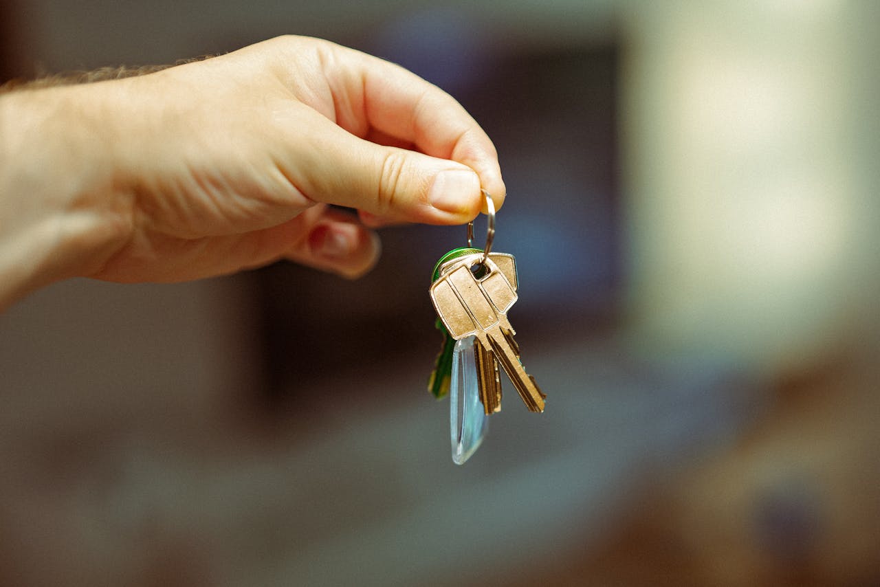 about-01 A close-up image of a hand holding a keyring with several house keys, symbolizing real estate and home ownership.