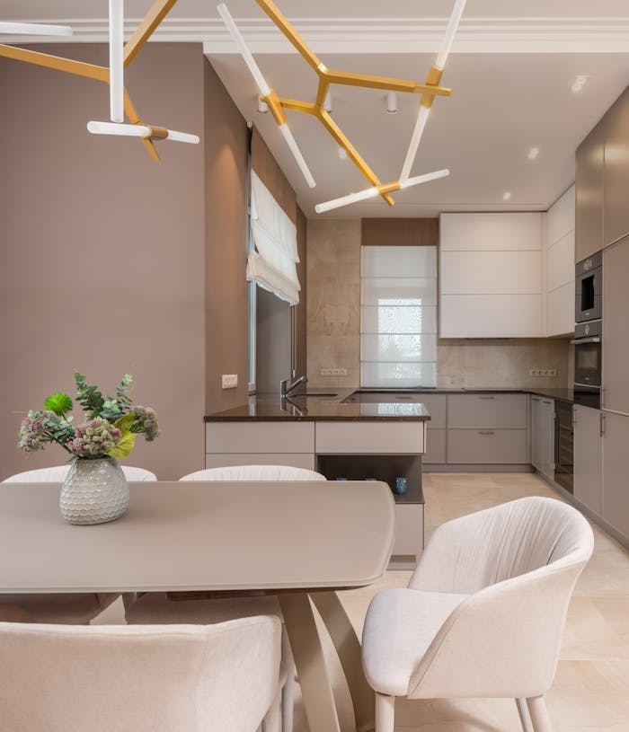 our-services-1 A stylish, open-plan kitchen and dining area featuring neutral tones, modern furniture, and elegant lighting.